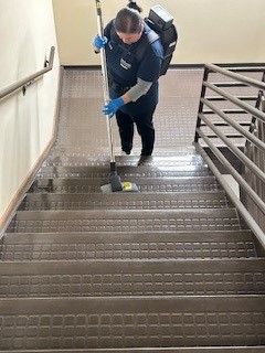A woman is cleaning the stairs with a mop.