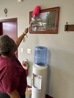A woman is cleaning a mirror with a duster in an office.