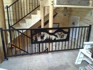Black metal railing with moose silhouette, inside a rustic wooden cabin.