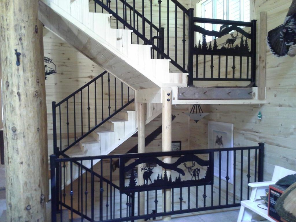 Wooden staircase with black metal railings, including wildlife silhouettes, in a cabin-like interior.