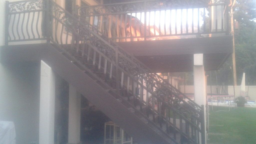 Exterior staircase leading to a balcony with decorative wrought iron railings.