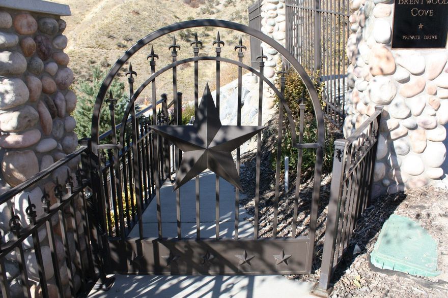 Black wrought-iron gate with a star emblem. Stone walls frame the gate.