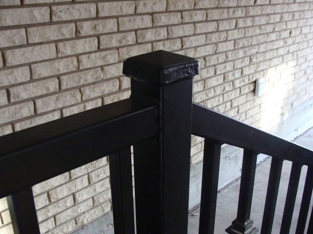 Black painted railing with brick wall background.