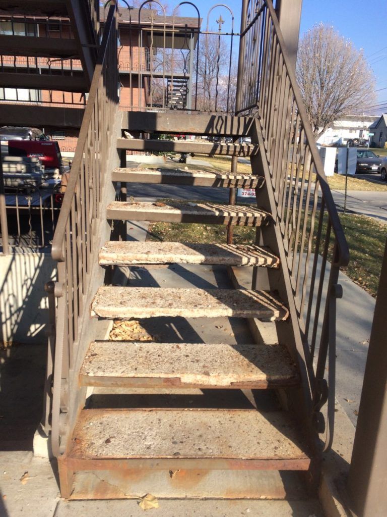 Outdoor, metal staircase with rust. Sunlight casts shadows.