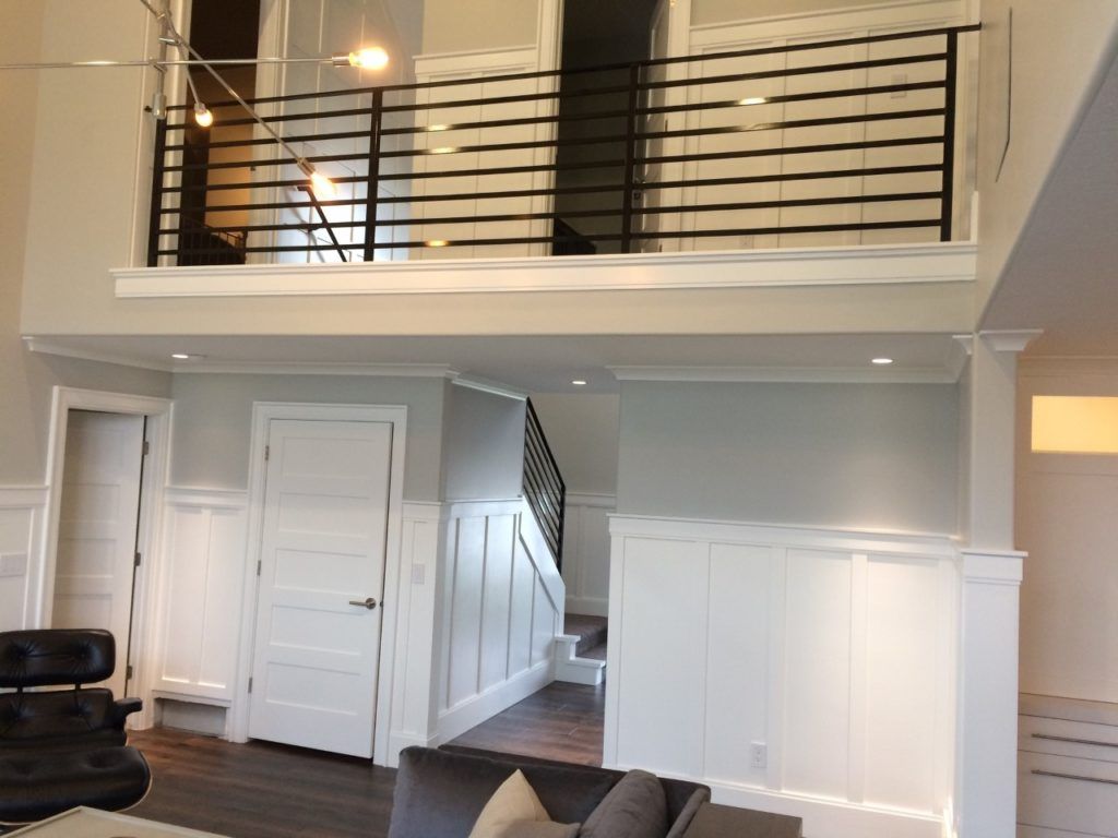 Two-story interior with a mezzanine. White trim, gray walls, black staircase, and black railing.