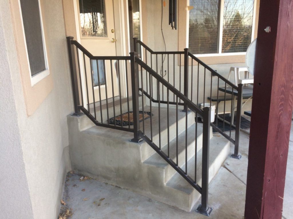 Exterior concrete steps with dark metal handrails leading to a doorway.