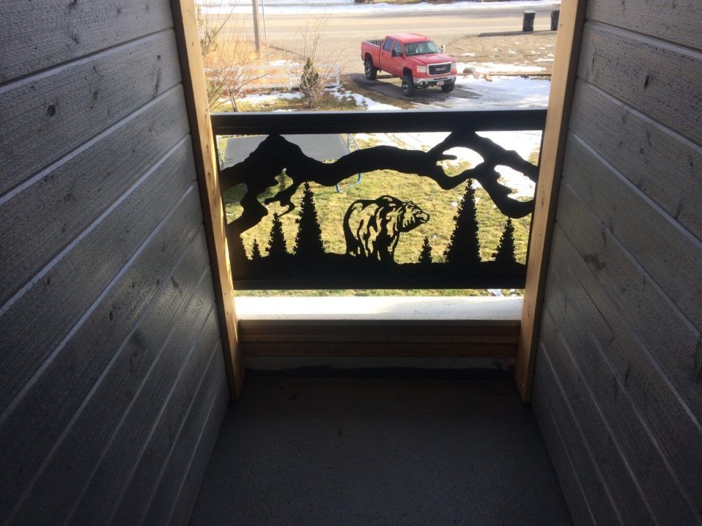 Wooden hallway with metal cut-out bear scene railing overlooking a red truck in winter.