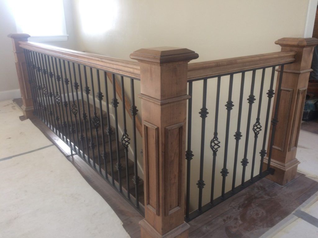 Wooden staircase railing with black metal spindles and decorative accents.