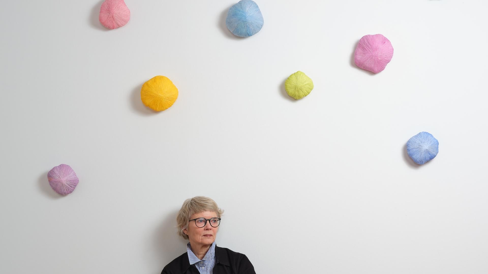Pastel litaðir skúlptúrar á vegg undir listamanninum sjálfum Guðrúnu Gunnarsdóttur.
