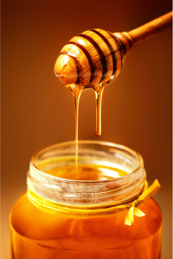 A jar of honey with a honey dipper sticking out of it