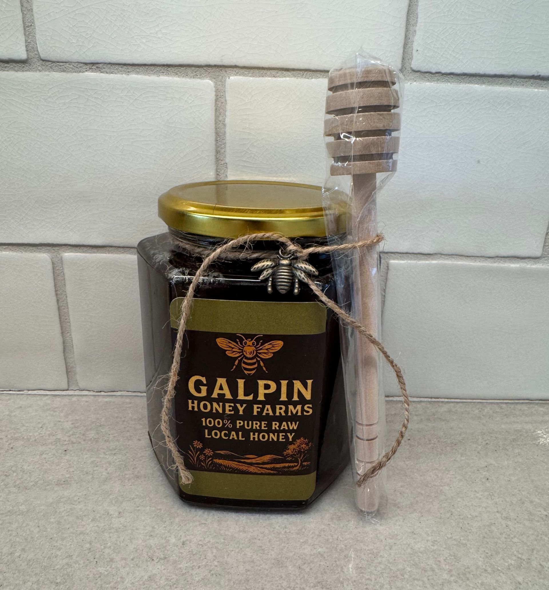 A jar of galpin honey farms honey next to a wooden dipper