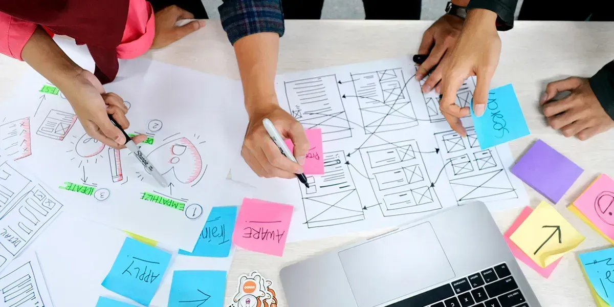 People collaborating on diagrams and notes, using sticky notes and a laptop.