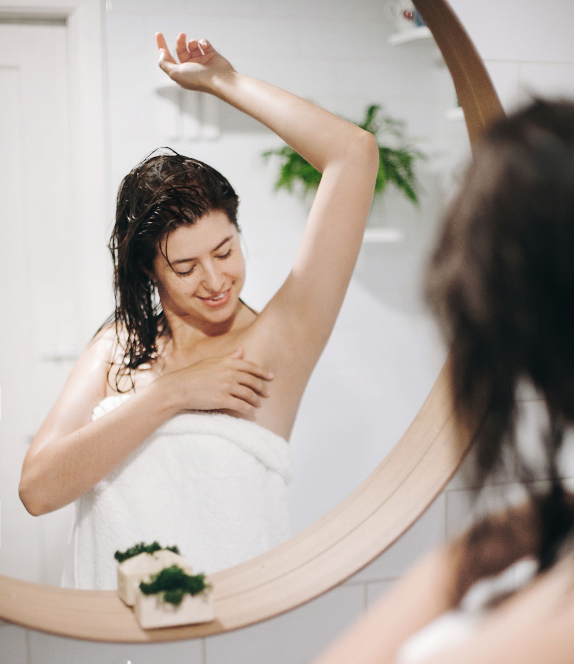 woman looking at underarms in mirror
