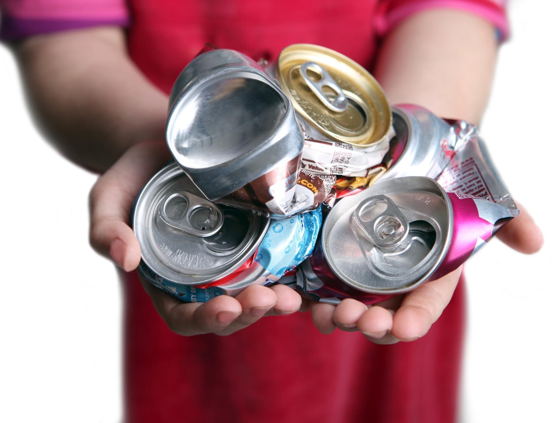 A person is holding a pile of crushed cans in their hands