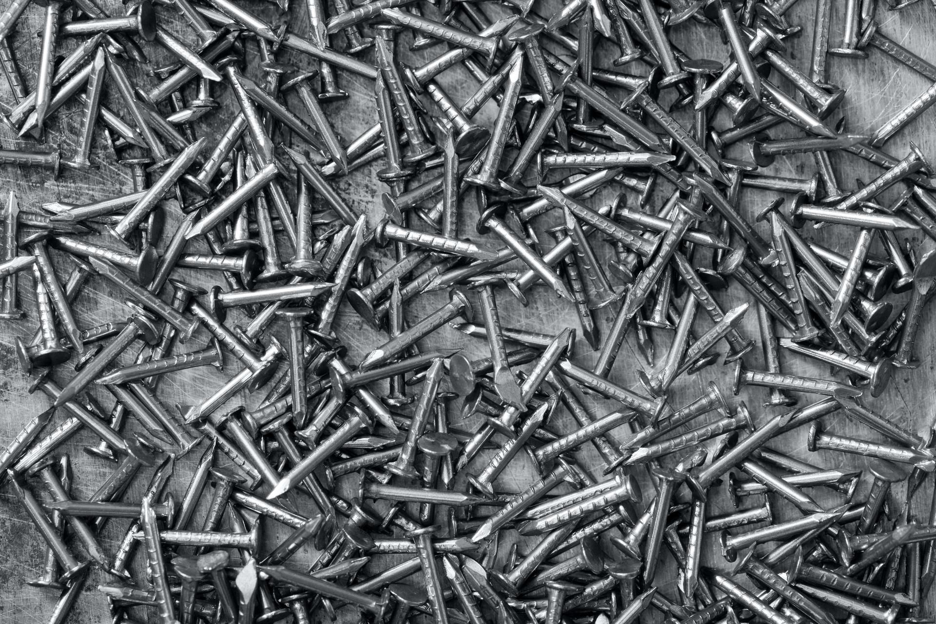 A pile of nails on a table in a black and white photo.