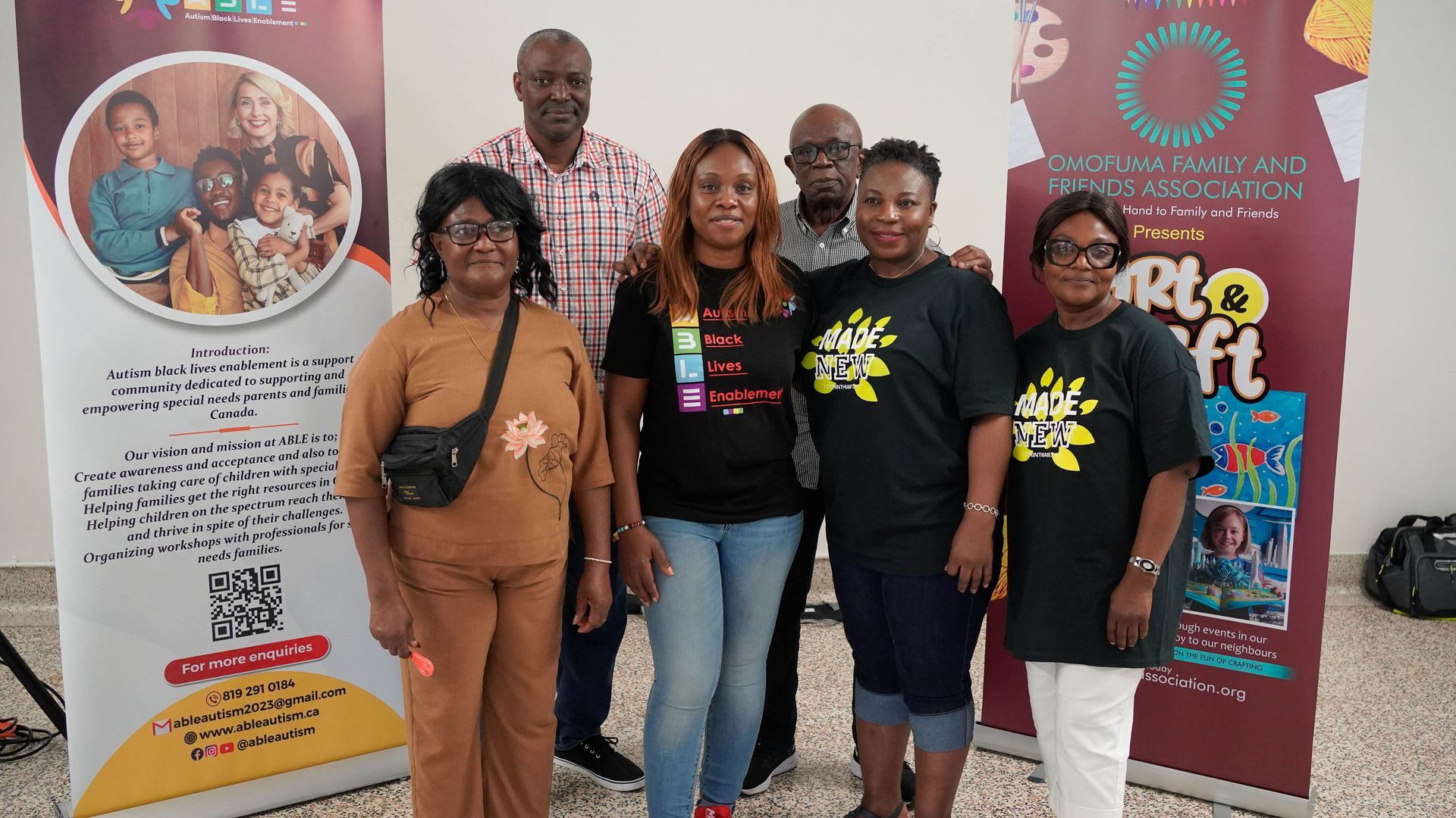 Group of people at an event, posing in front of banners. Some wearing themed t-shirts, smiling.