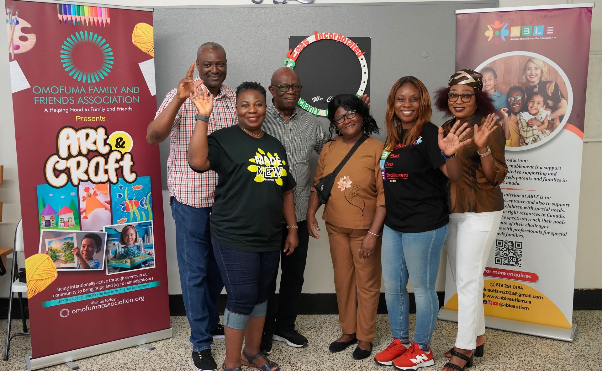 Group of adults waving near banners at an art event, indoors.