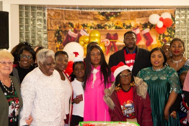 Group photo at Christmas event, diverse group smiling in front of festive decorations.