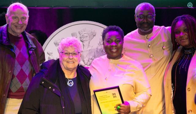 Group of people smiling, holding an award in front of a logo.