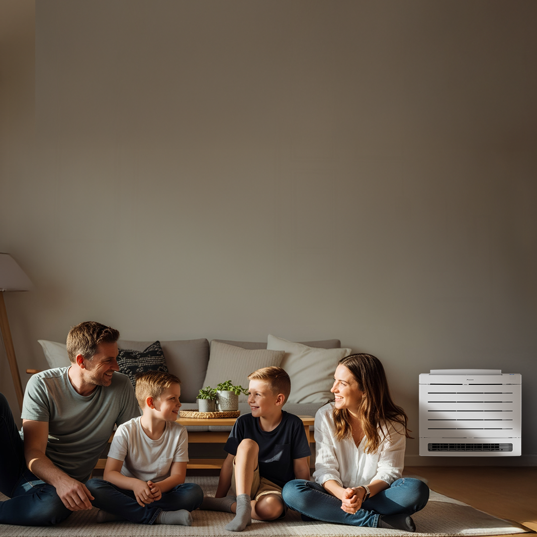 Family sitting on floor in front of Daikin Aura floor console unit.