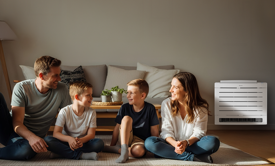 Family sat in front of couch next to Daikin Aura floor console heat pump