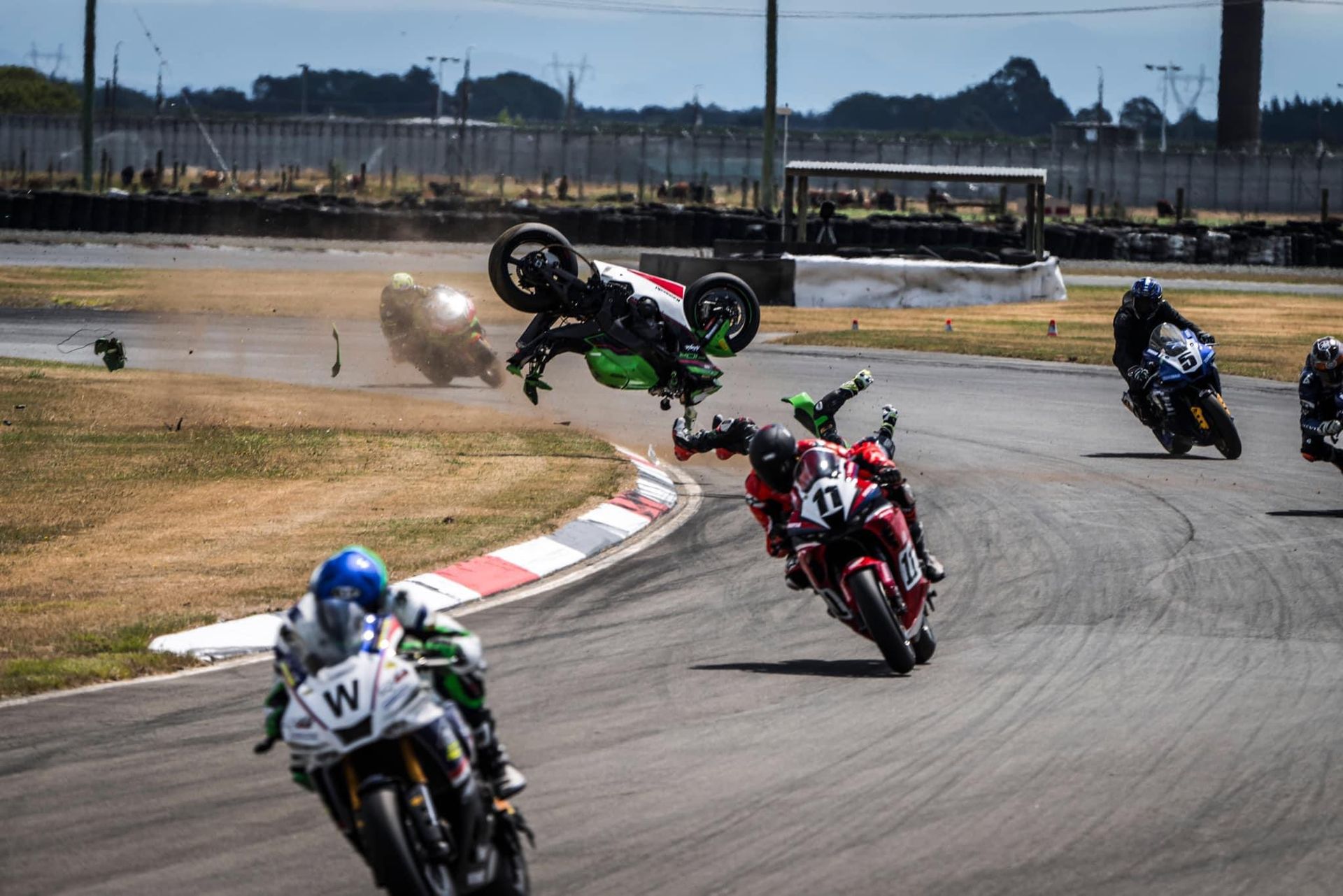 Dale Finch motorbike crash.   Dale's motorbike flying through the air on the race track and Dale about to land on the track whilst motorbikes are racing.