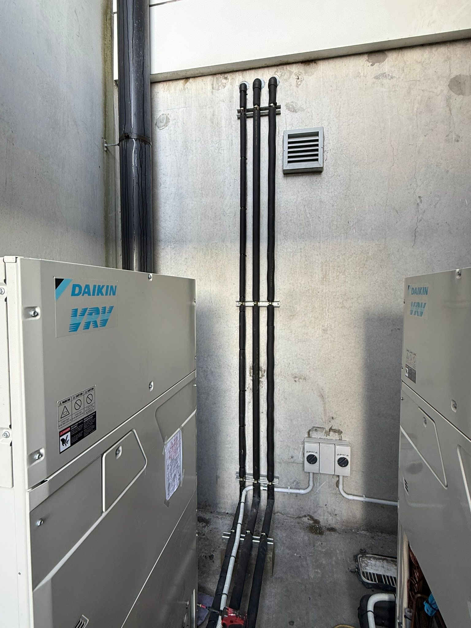 Daikin VRV outdoor units with air conditioning pipework and isolator switches. 