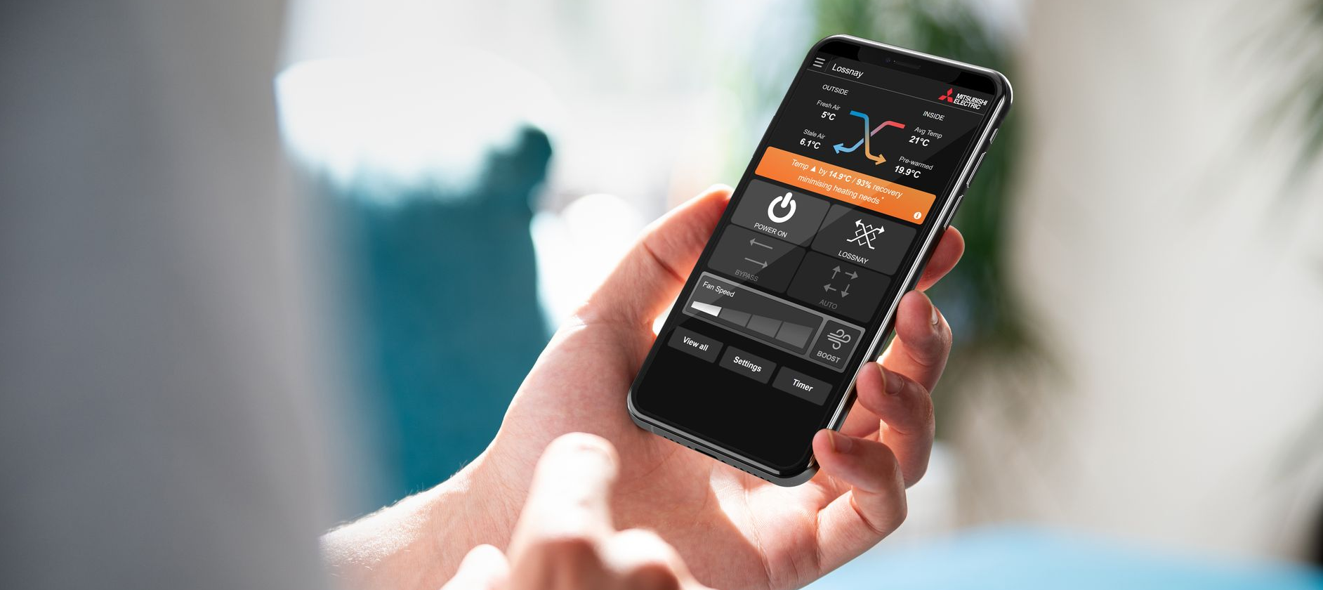 Person holding cell phone with Mitsubishi Electric Lossnay app.