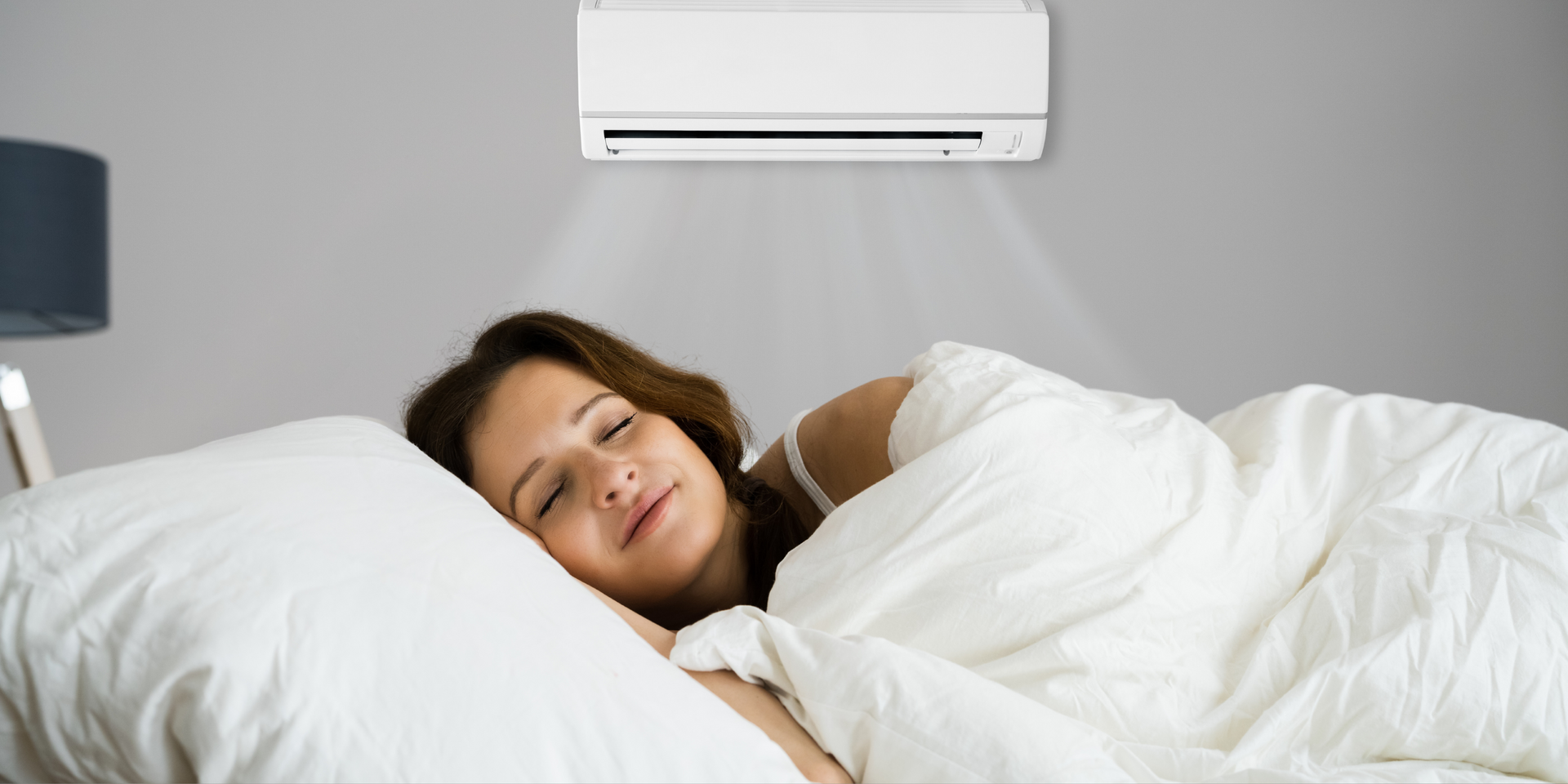 Woman asleep in bedroom with air conditioner blowing cool air