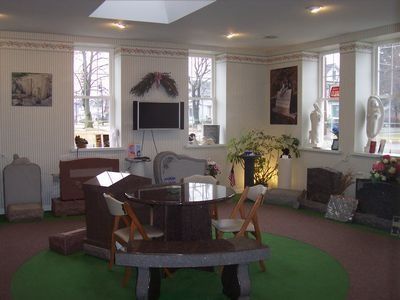 Interior of a monument showroom with various headstones, seating, and decorative elements.