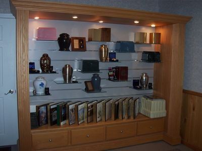Wooden display case with cremation urns, keepsakes, and service booklets.