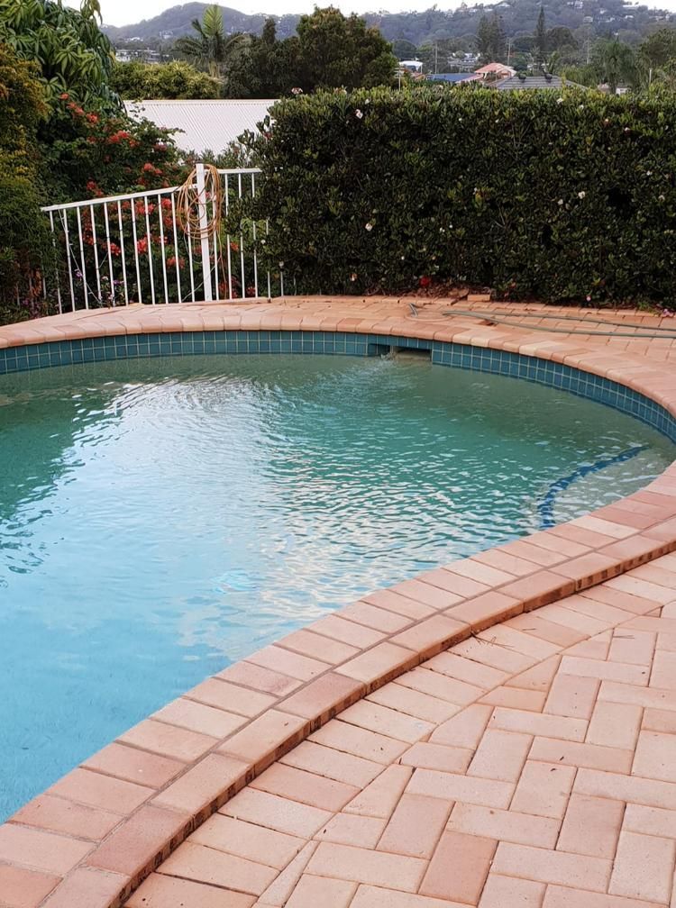 A Swimming Pool With A Brick Border And A White Railing — Kingscliff Pool Shop In Kingscliff, NSW