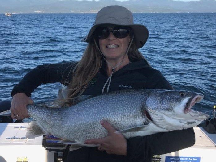 A woman is holding a large fish on a boat.