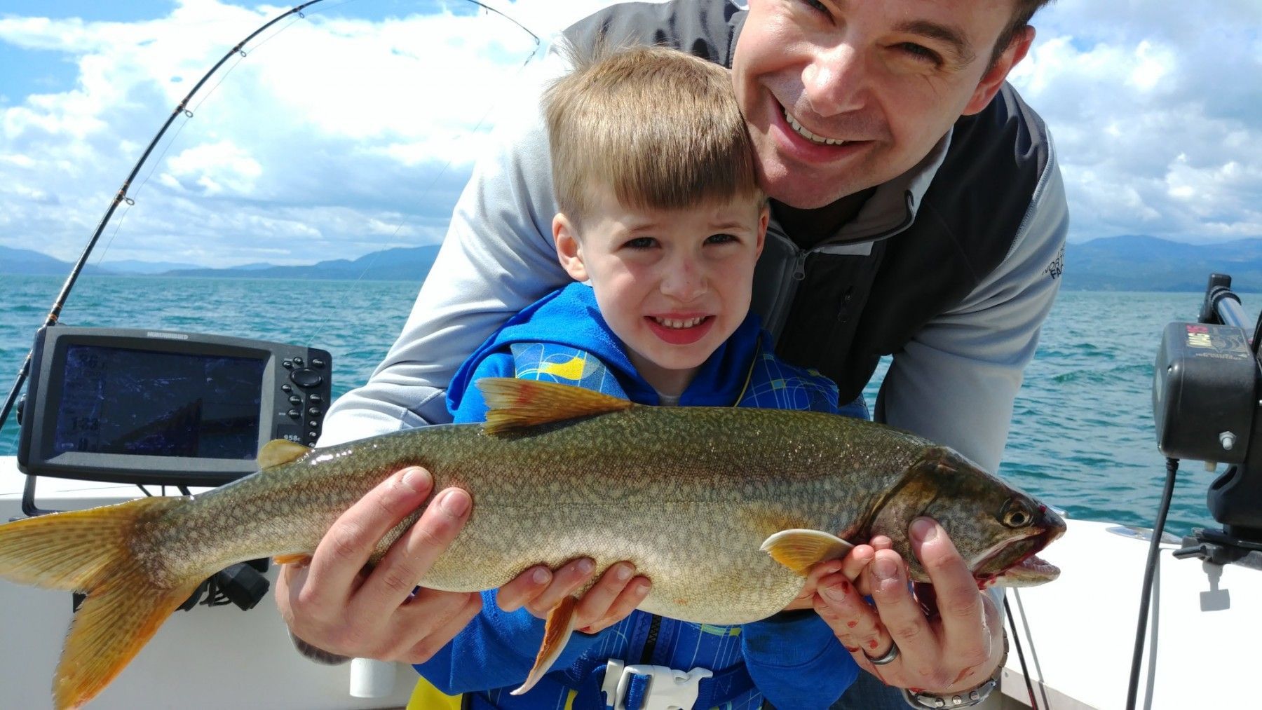 A man and a boy are holding a large fish on a boat.