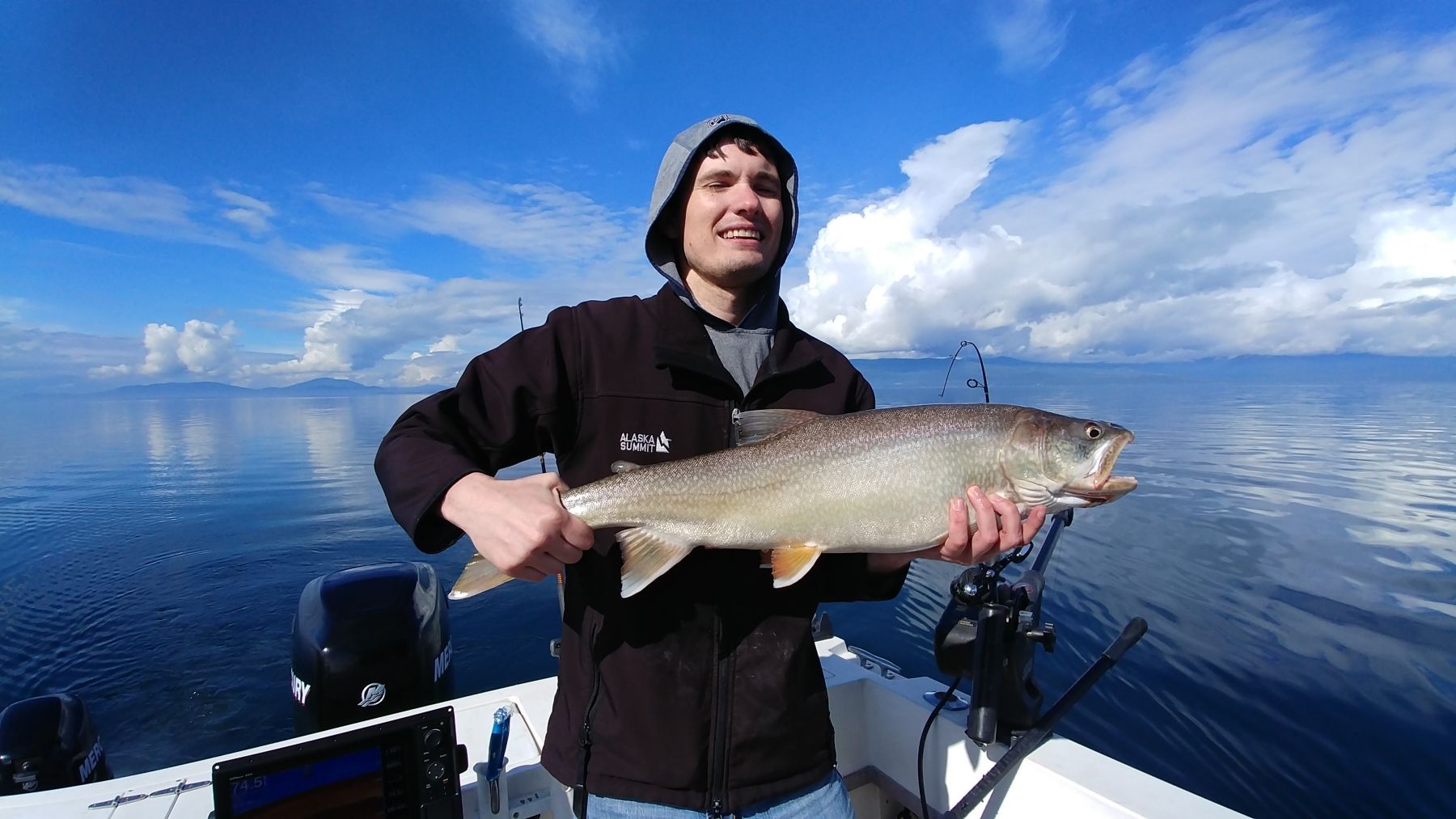 A man is holding a large fish on a boat in the water.