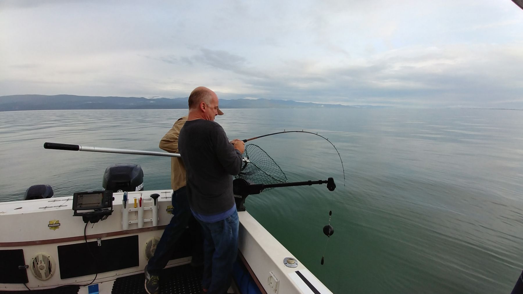 A man is fishing on a boat in the ocean