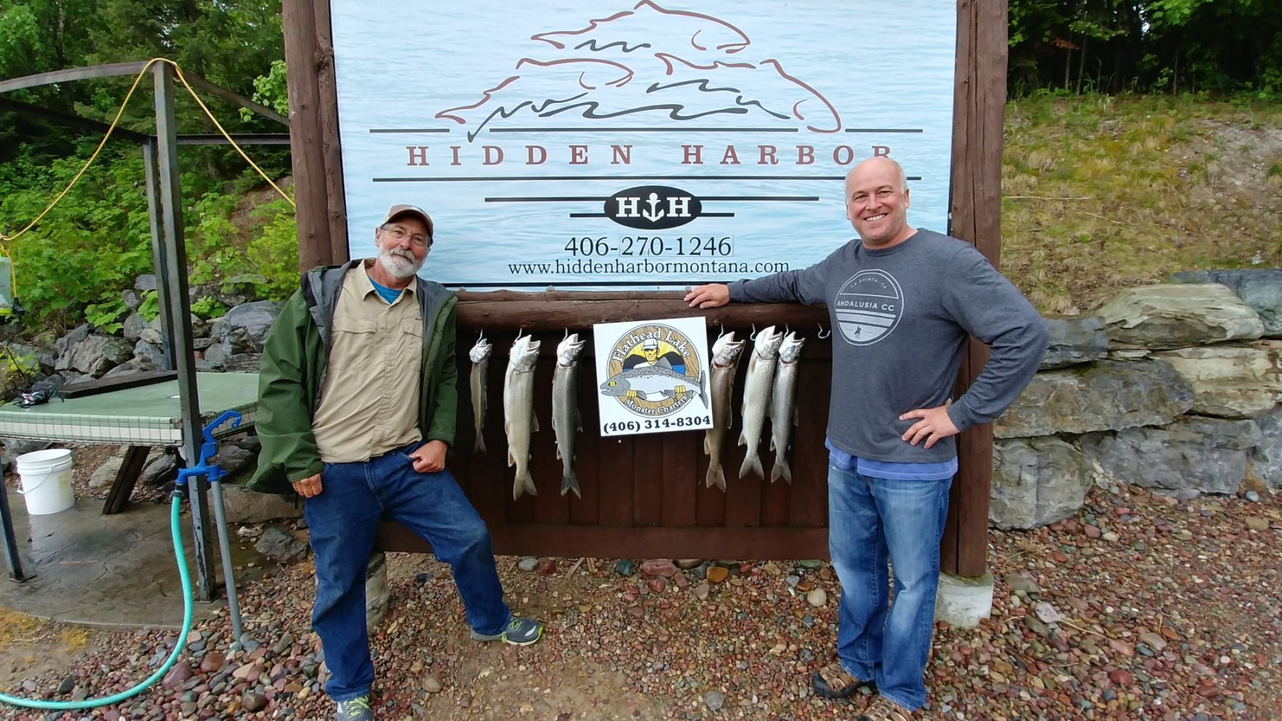 Two men standing in front of a sign that says hidden harbor