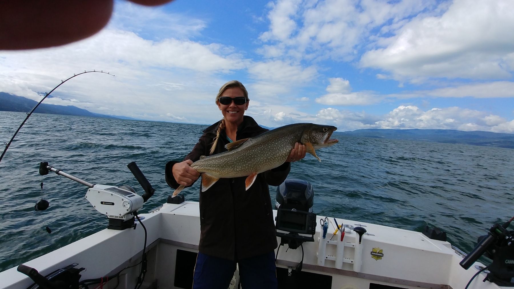 A woman is holding a large fish on a boat in the water.