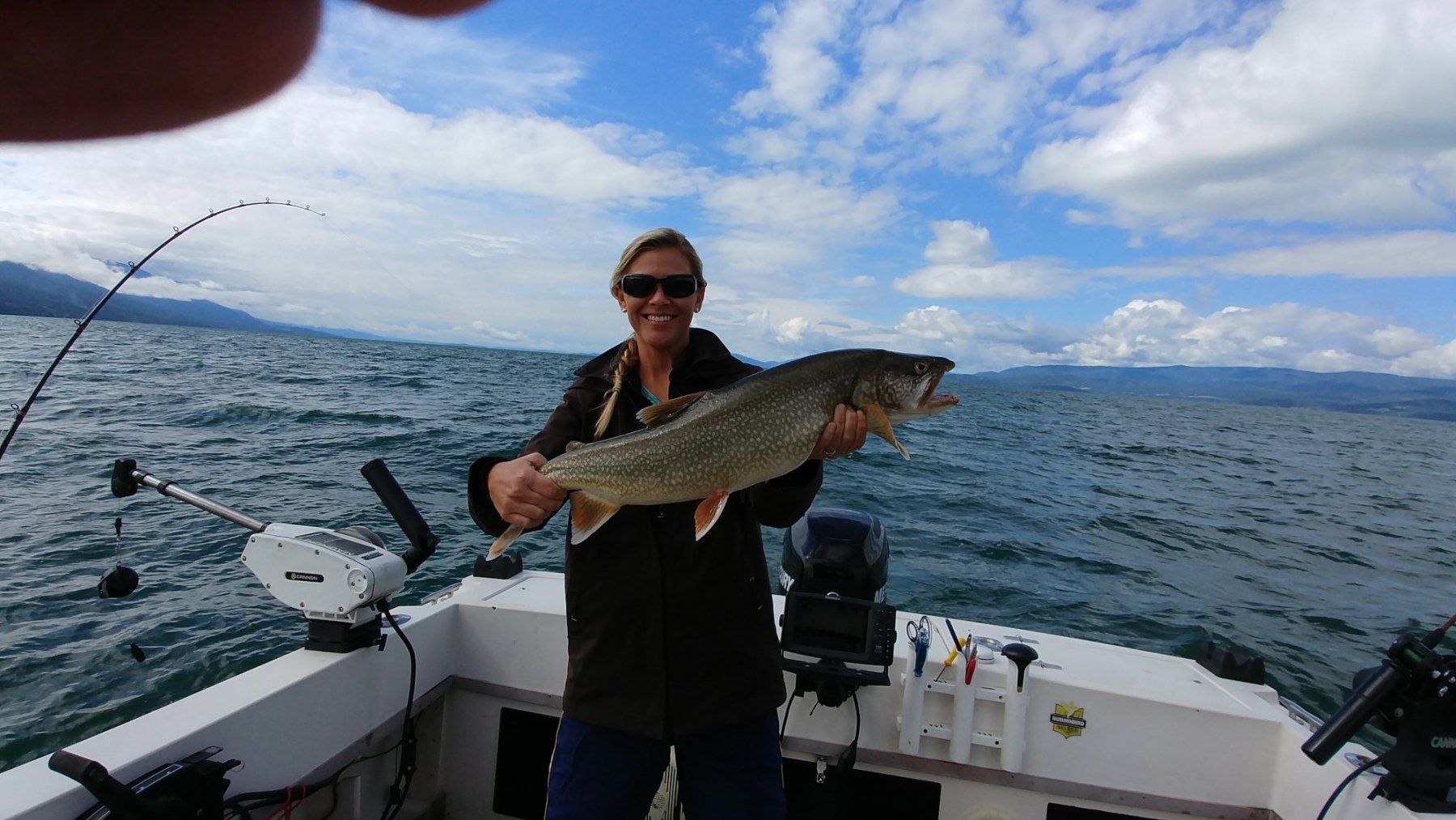 A woman is holding a large fish on a boat.