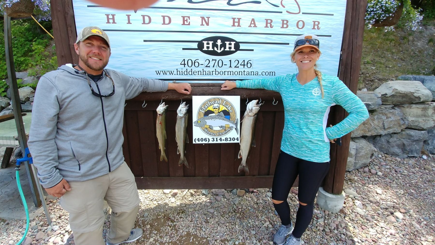 A man and a woman are standing in front of a sign that says hidden harbor