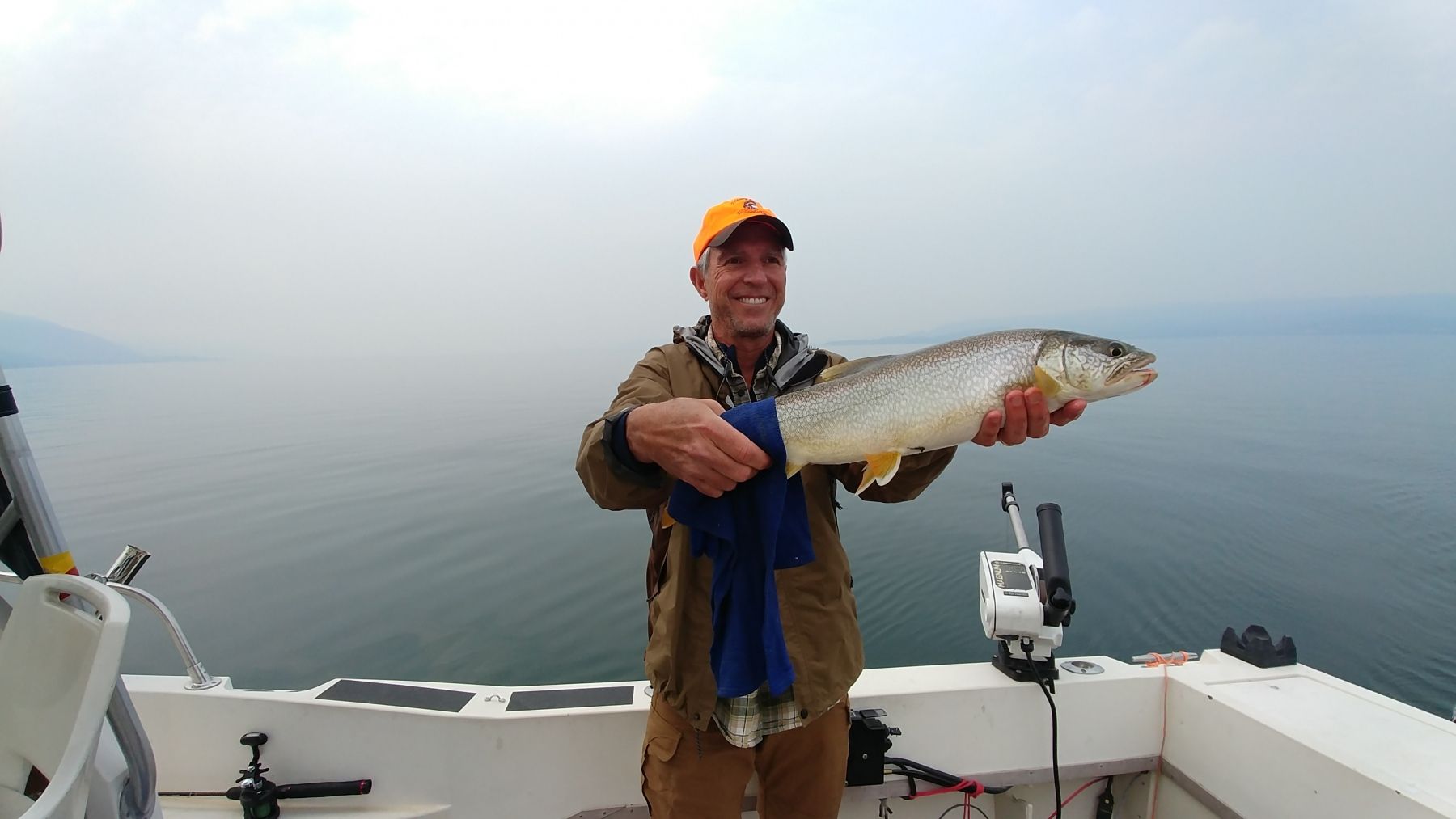 A man is holding a large fish on a boat.