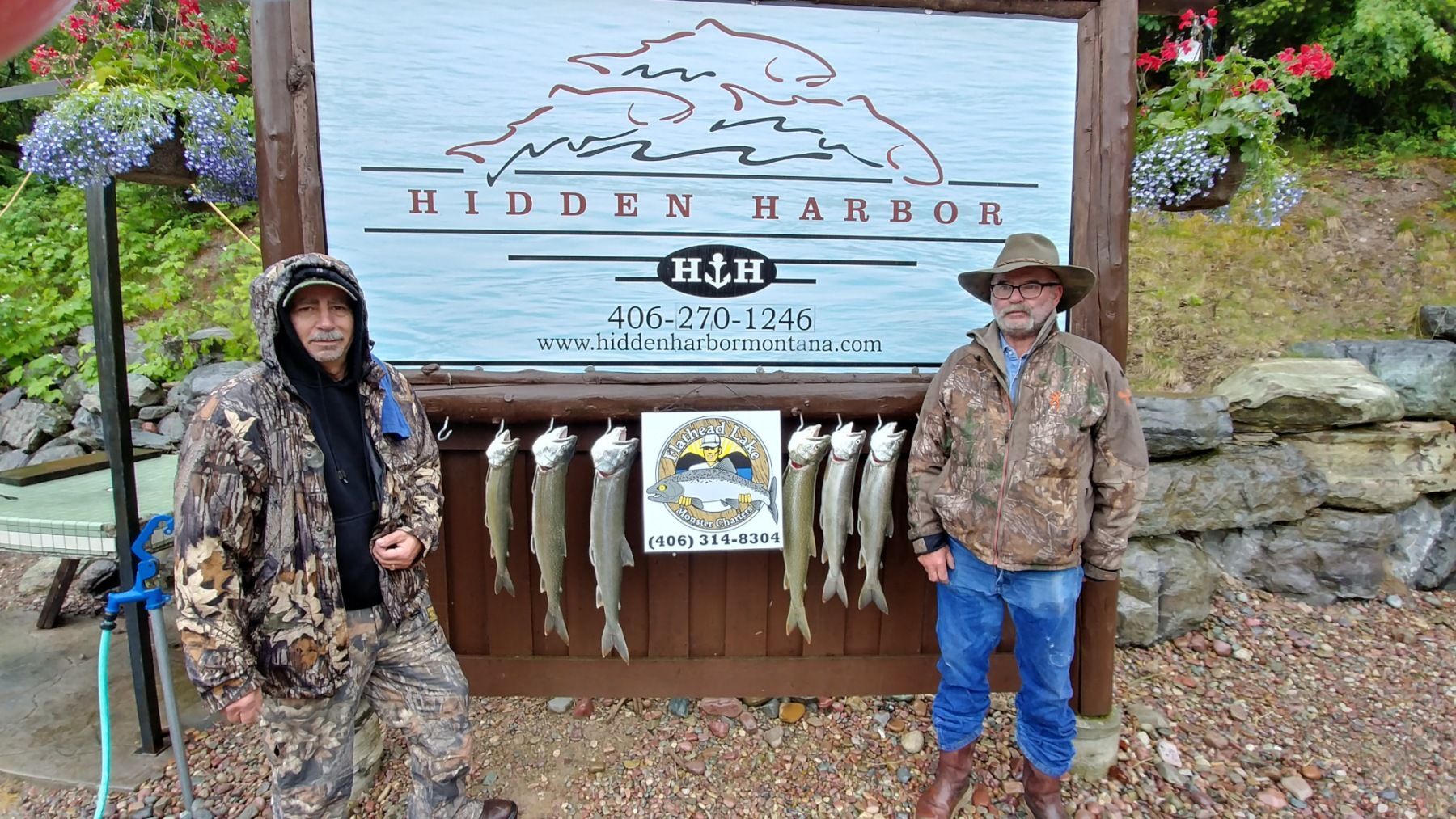 Two men are standing in front of a sign that says hidden harbor