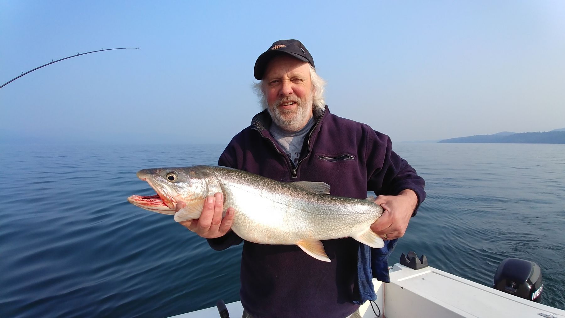 A man is holding a large fish on a boat.