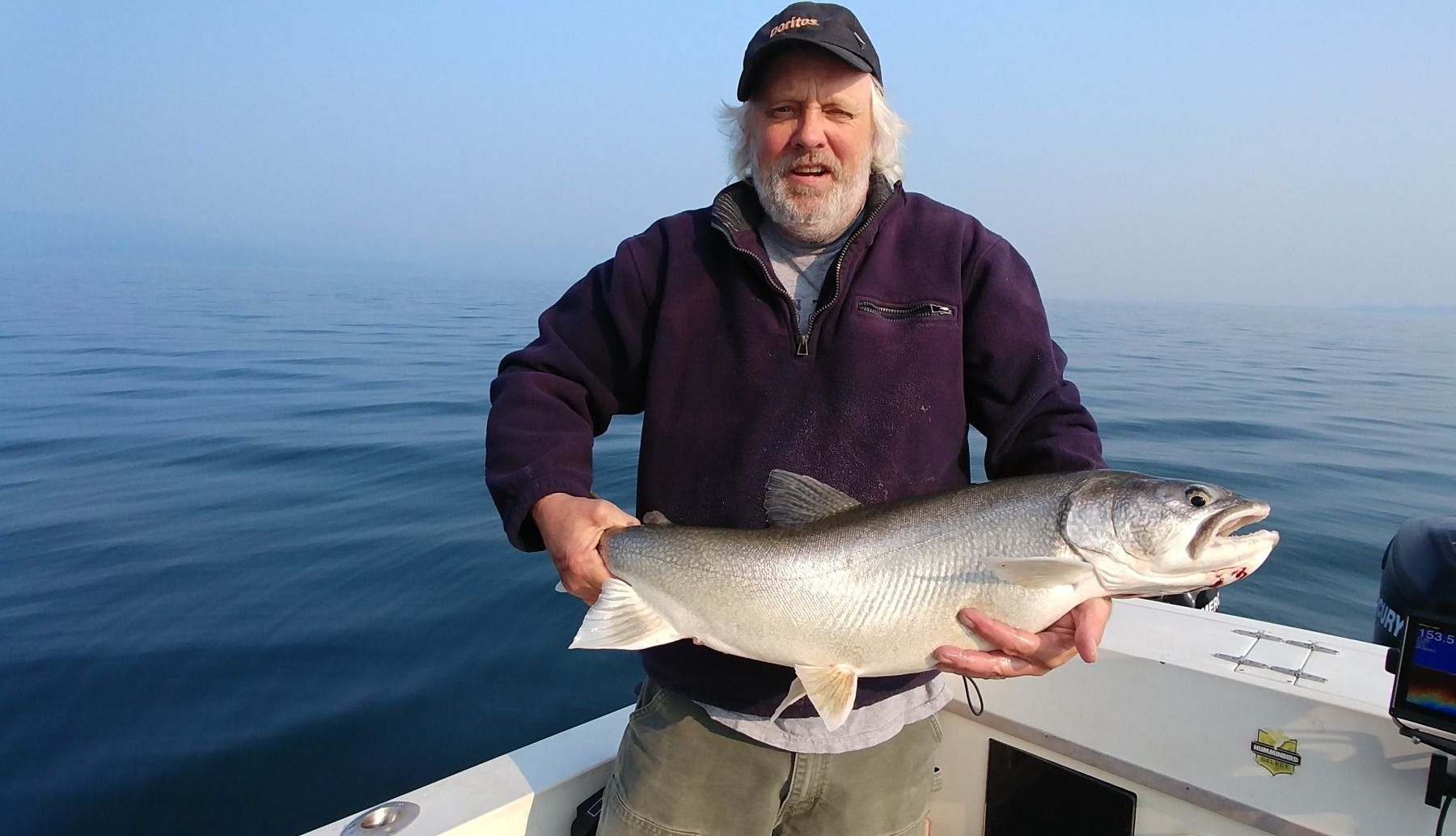 A man is holding a large fish on a boat.