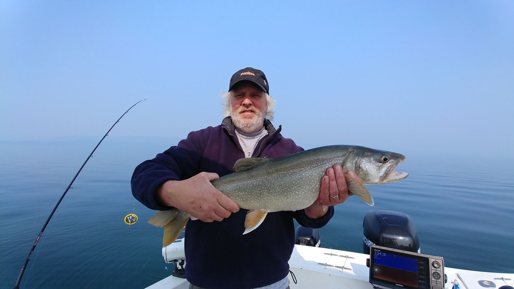 A man is holding a large fish on a boat.