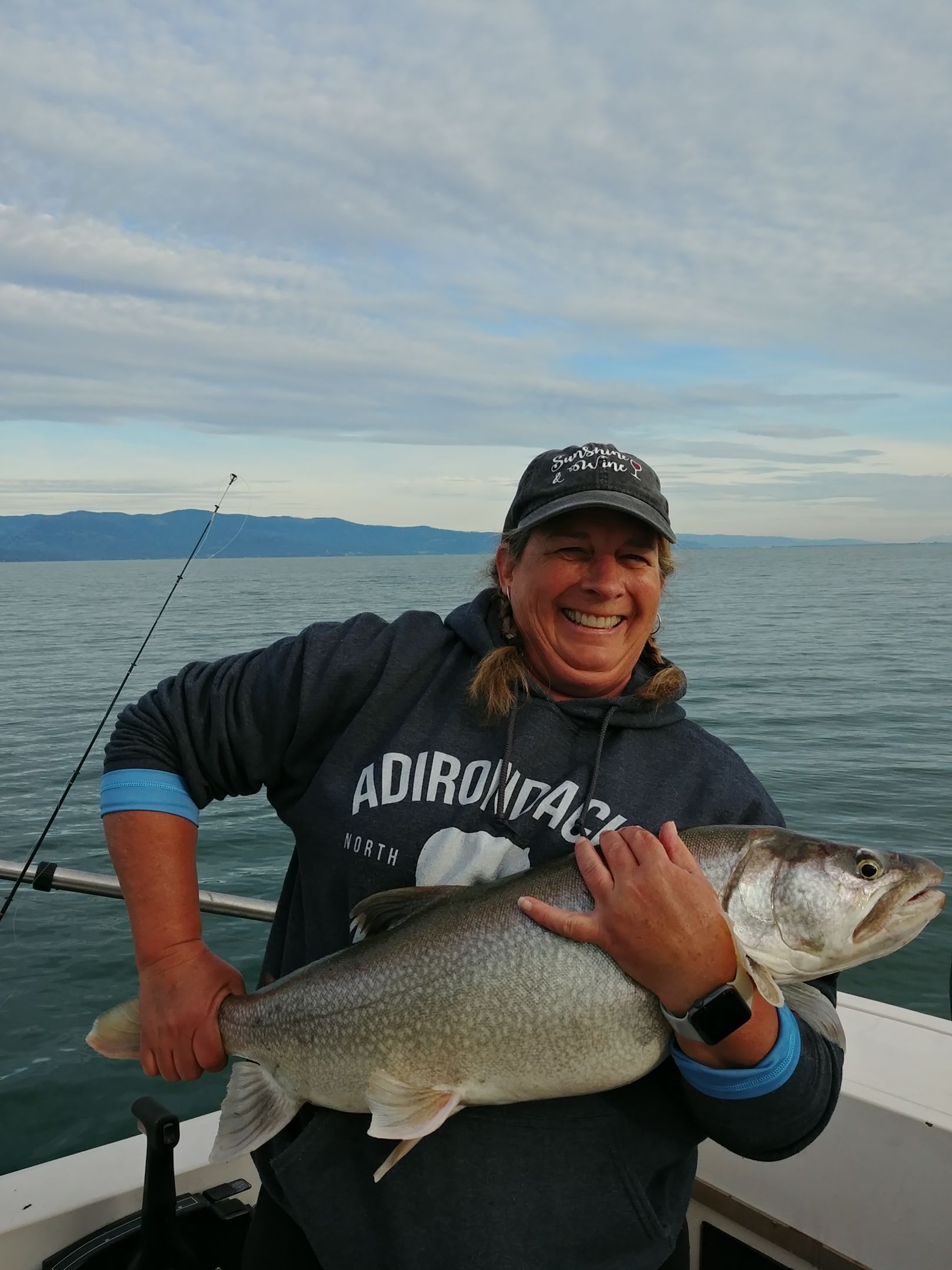 A woman is holding a large fish on a boat.