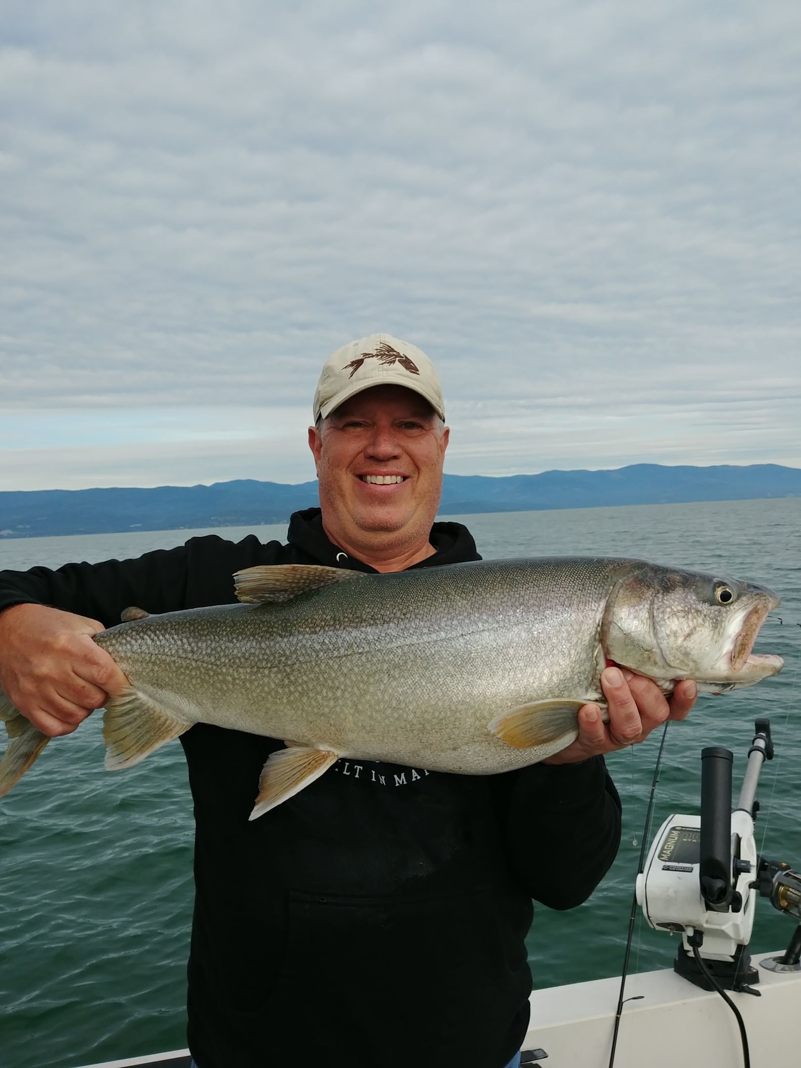 A man is holding a large fish in his hands on a boat.