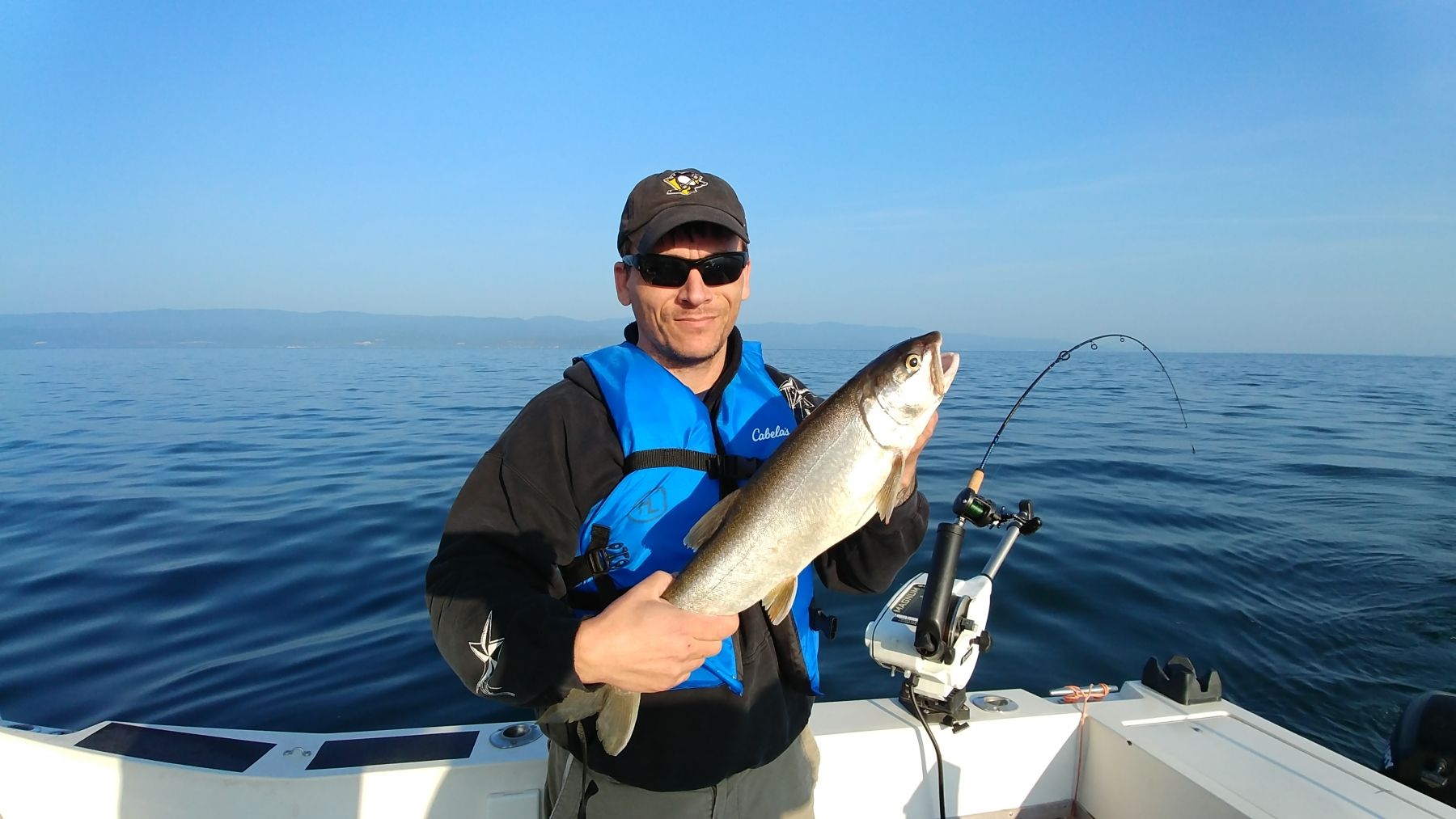 A man is holding a fish on a boat in the ocean.