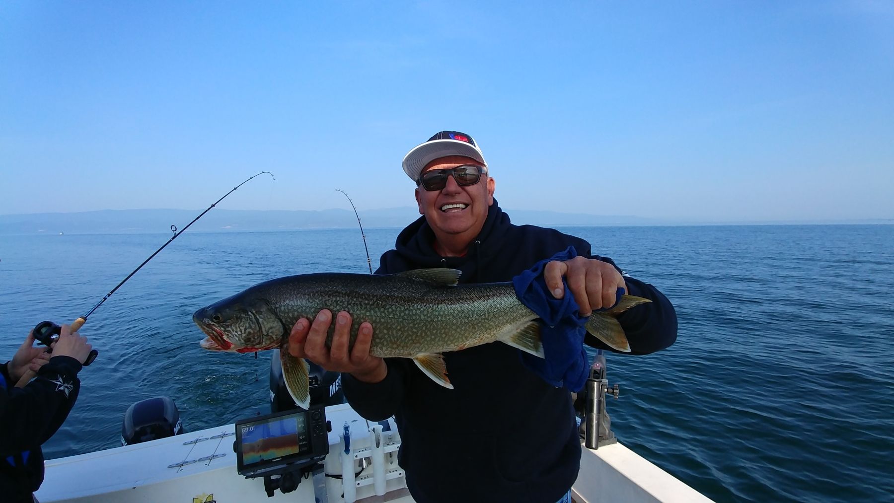 A man is holding a fish while fishing on a boat.
