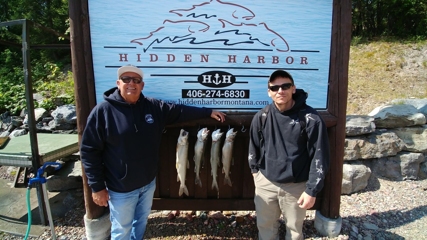Two men standing in front of a sign that says hidden harbor